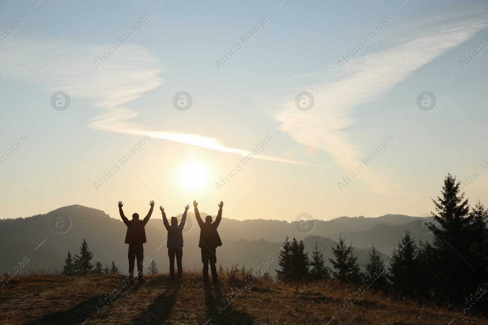 Photo of Group of people enjoying sunrise in mountains, back view. Space for text