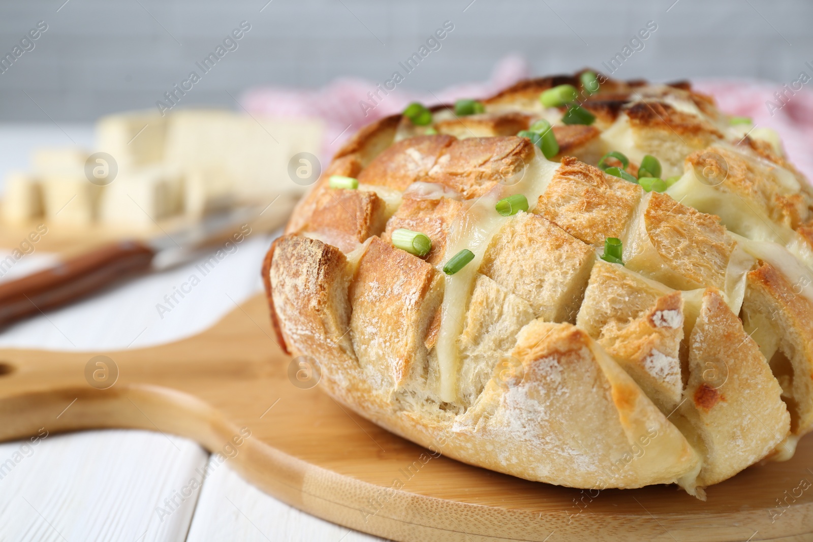 Photo of Freshly baked bread with tofu cheese and green onions on white wooden table, closeup