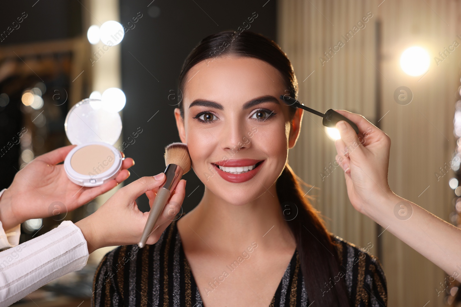 Photo of Makeup artists working with beautiful woman in dressing room