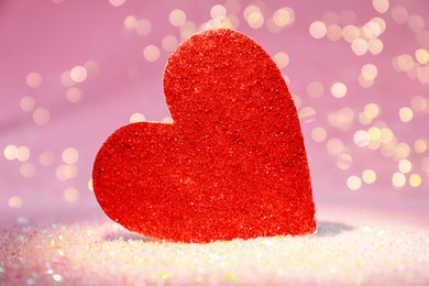 Photo of Red decorative heart on glitter against blurred lights, closeup