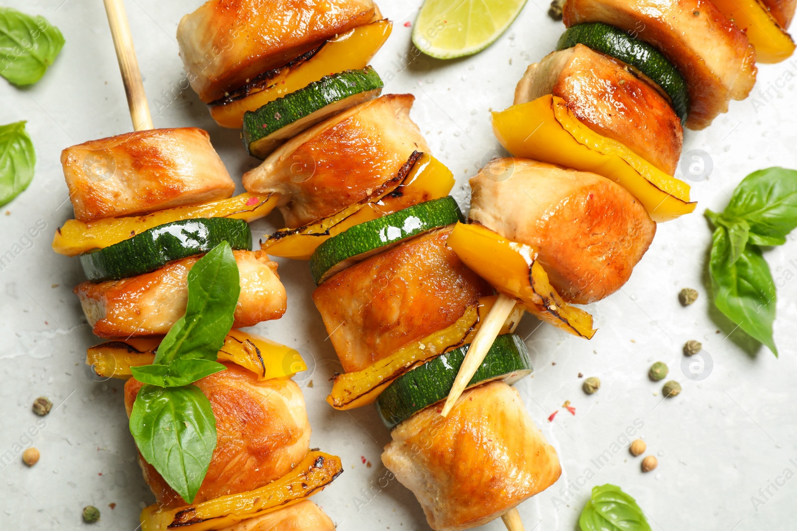 Photo of Delicious chicken shish kebabs with vegetables on grey marble table, flat lay