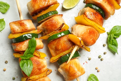 Delicious chicken shish kebabs with vegetables on grey marble table, flat lay