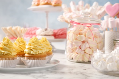 Candy bar with different sweets on white marble table. Space for text