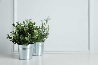 Photo of Aromatic potted herbs on wooden table near white wall, space for text