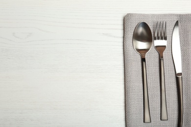 Photo of Cutlery and napkin on light wooden background, top view. Table setting