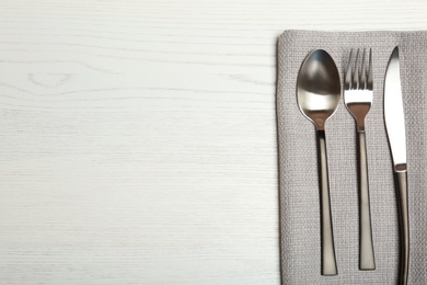 Cutlery and napkin on light wooden background, top view. Table setting