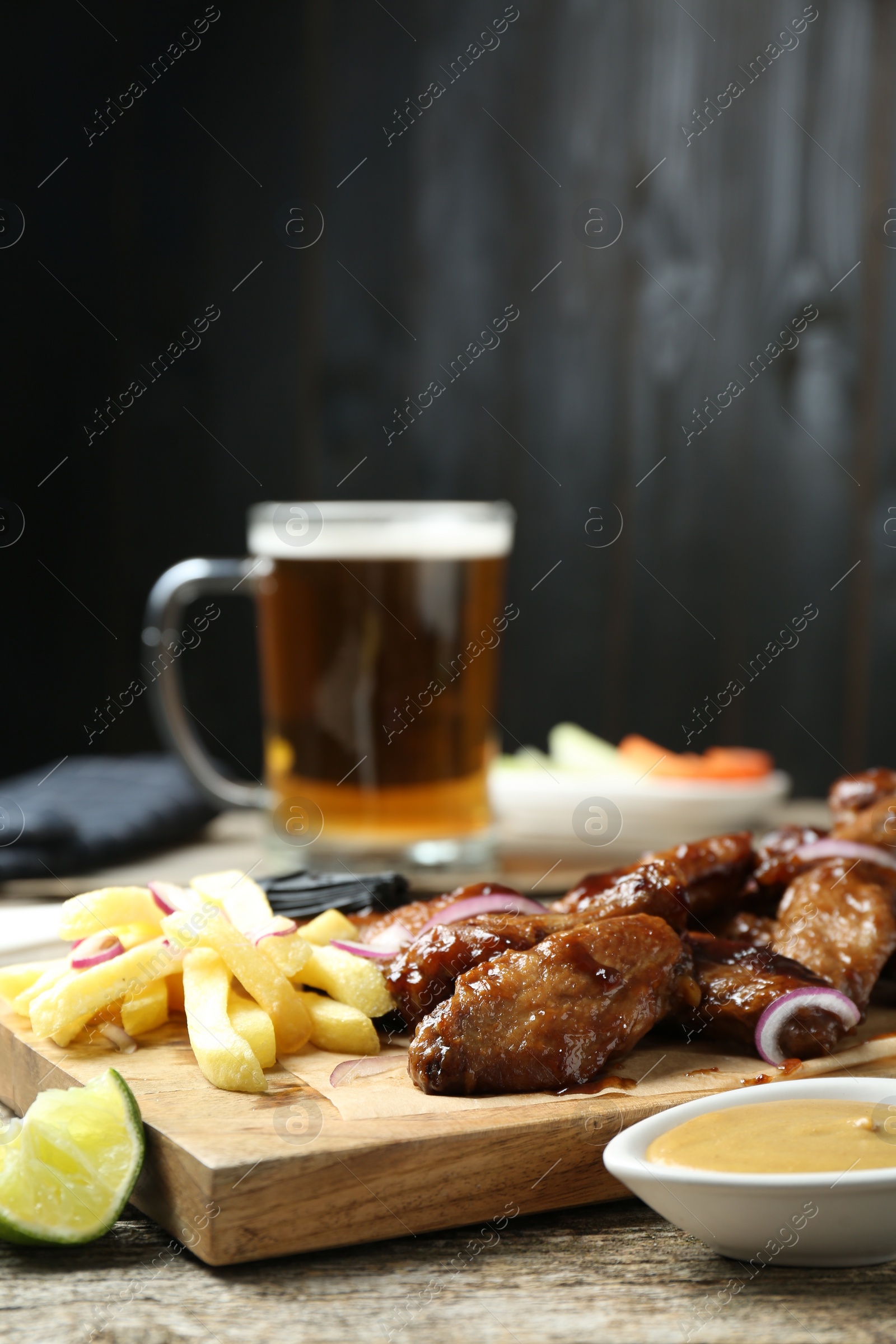 Photo of Tasty roasted chicken wings served with beer on wooden table, closeup