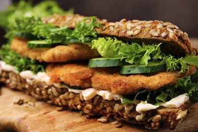 Photo of Delicious sandwich with schnitzel on wooden table, closeup