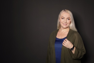 Portrait of mature woman on black background. Space for text