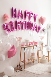 Phrase HAPPY BIRTHDAY made of pink balloon letters in decorated room