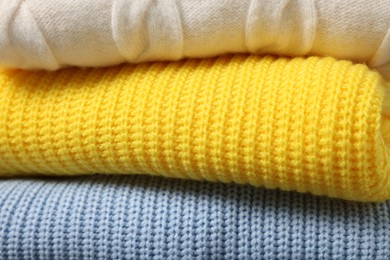 Photo of Stack of casual warm sweaters as background, closeup view