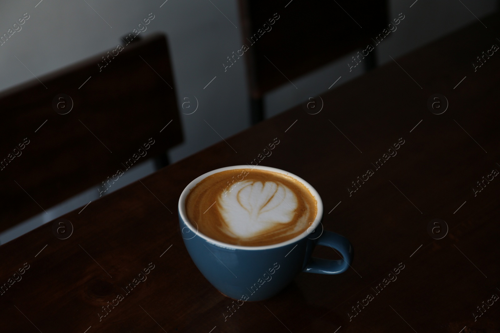 Photo of Cup of aromatic coffee on wooden table in cafe