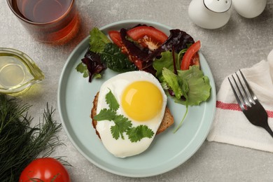 Photo of Delicious breakfast with fried egg and salad served on light grey table, flat lay