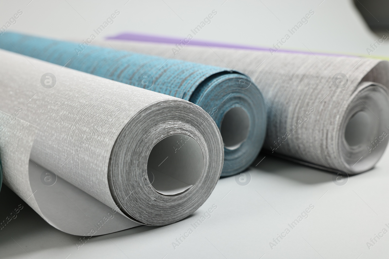 Photo of Different stylish wallpaper rolls on white background, closeup