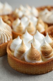 Photo of Many tartlets on grey table, closeup. Delicious dessert