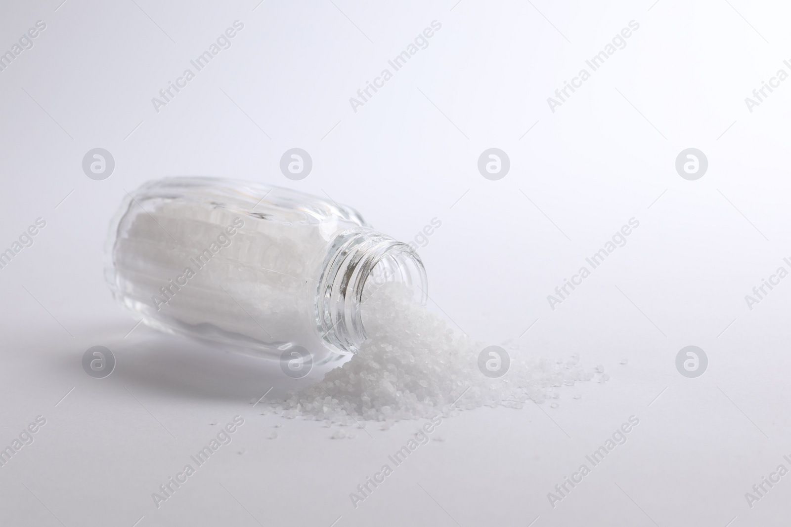 Photo of Natural salt in shaker on white background, space for text