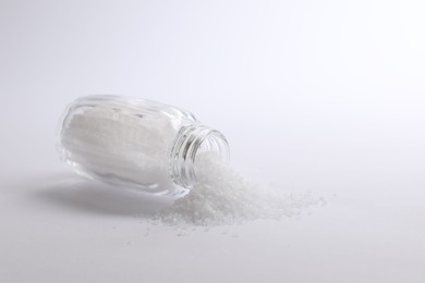 Photo of Natural salt in shaker on white background, space for text