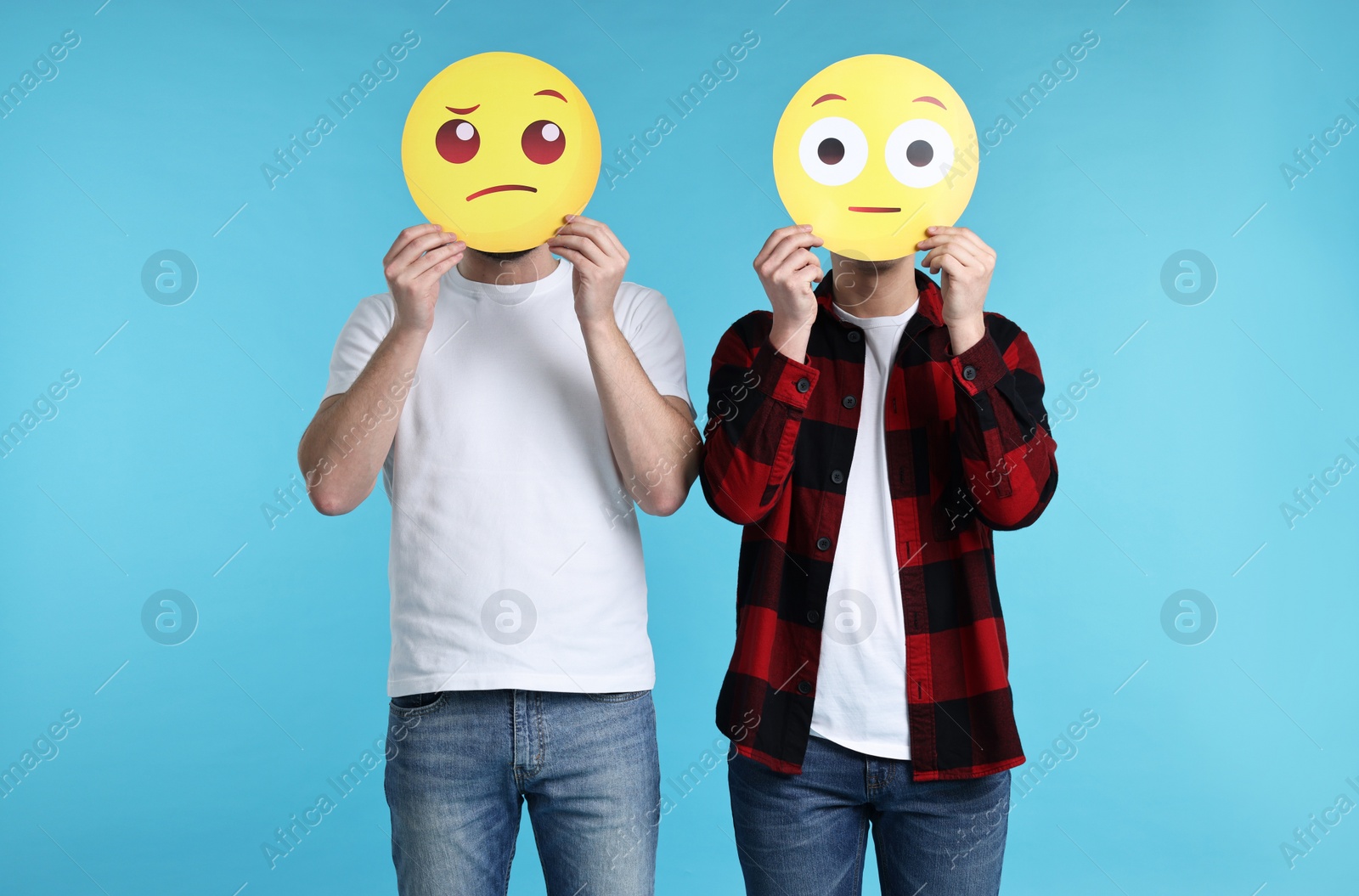 Photo of People covering faces with emoticons on light blue background