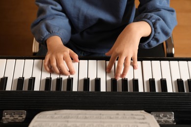 Photo of Little child playing piano, above view. Music lesson