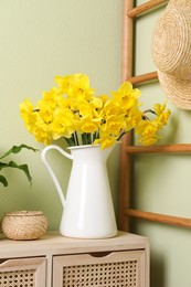 Jug with beautiful daffodils on table indoors