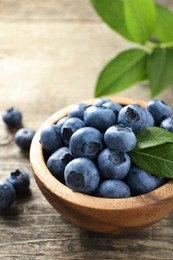 Bowl of fresh tasty blueberries on wooden table, closeup. Space for text