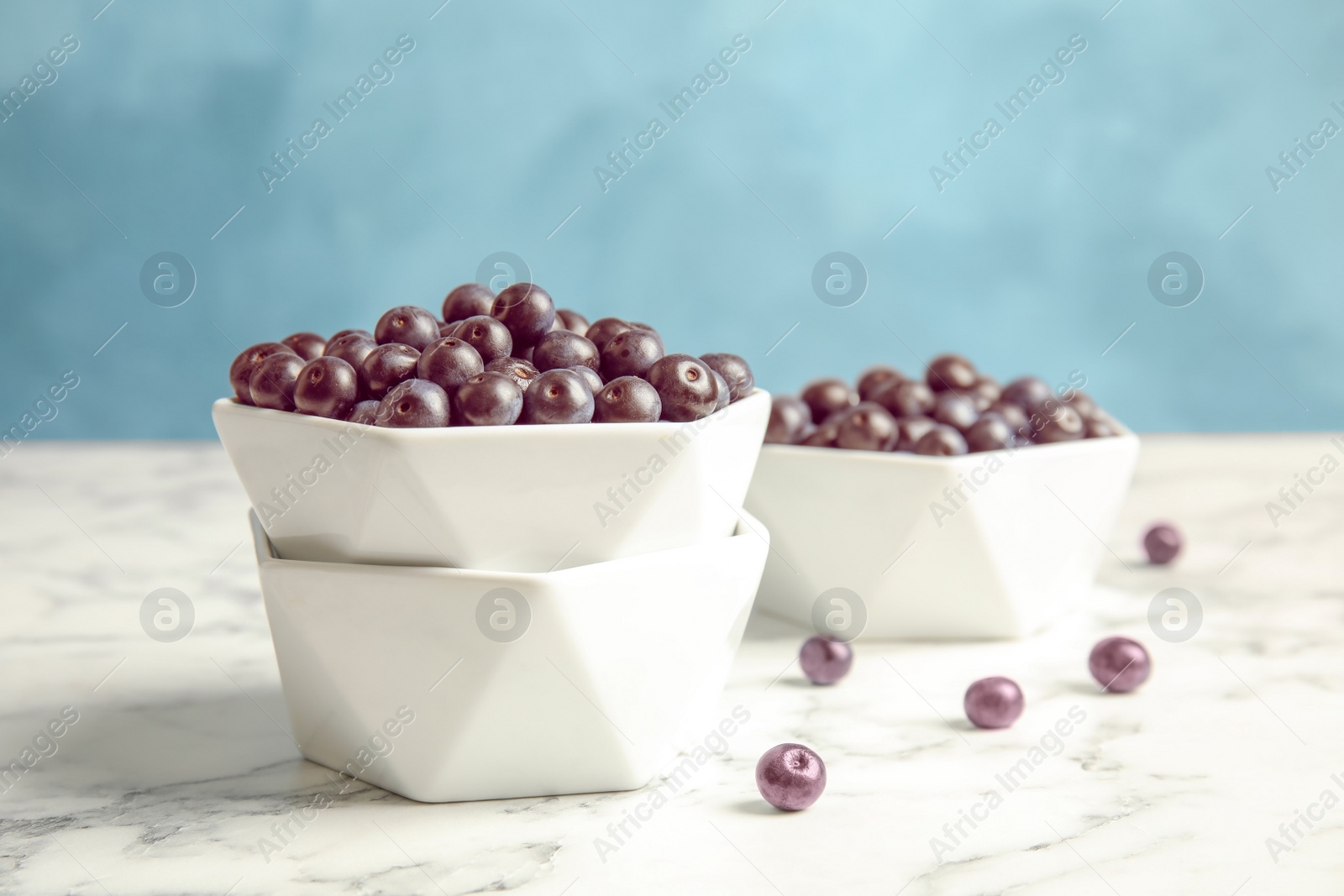 Photo of Bowls with fresh acai berries on marble table