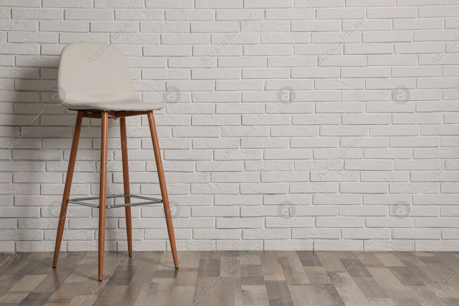 Photo of Stylish bar stool near white brick wall indoors. Space for text