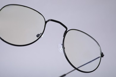 Stylish pair of glasses on light grey background, closeup