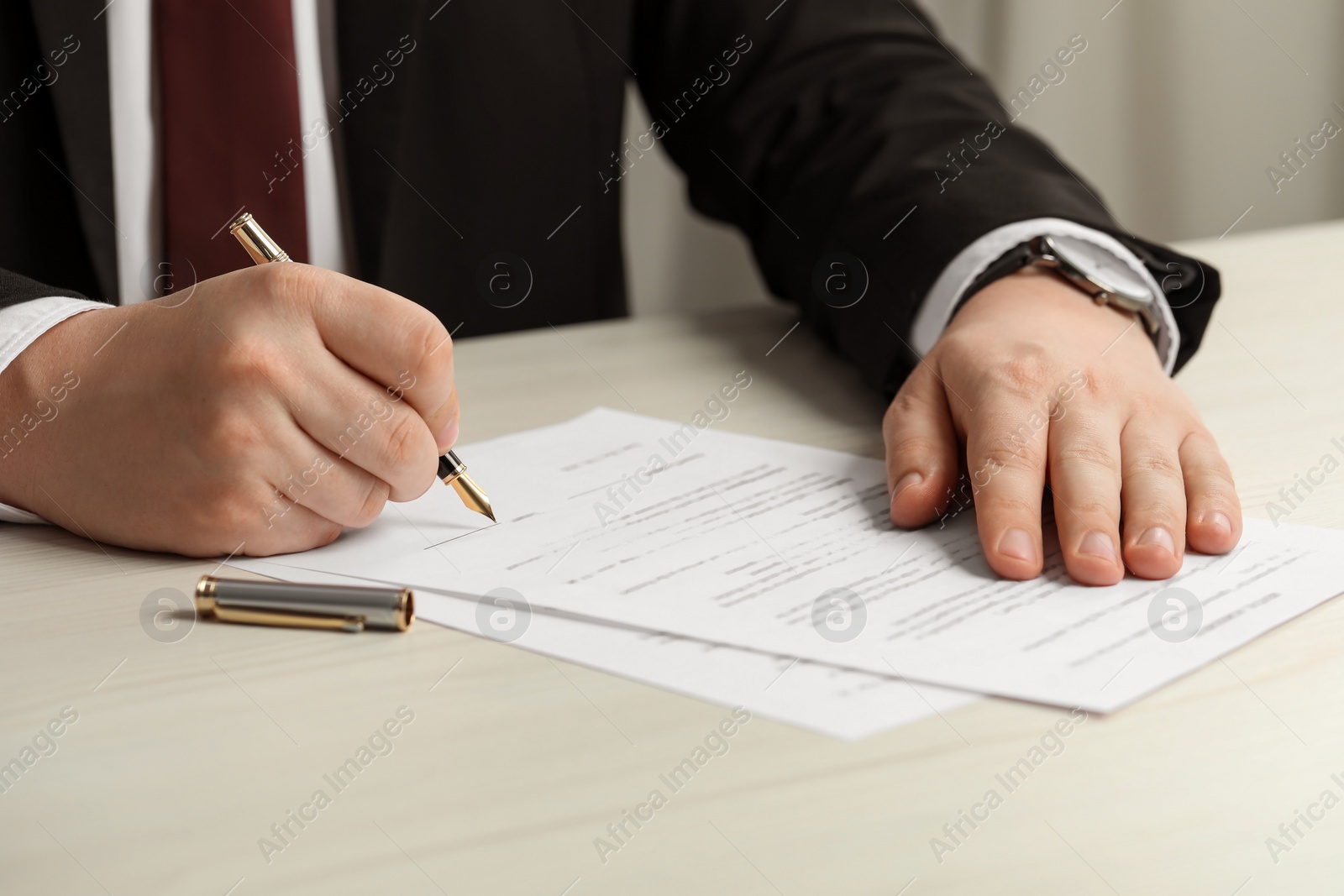 Photo of Notary signing document at wooden table, closeup