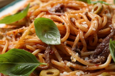 Photo of Delicious pasta with anchovies, tomato sauce and basil as background, closeup