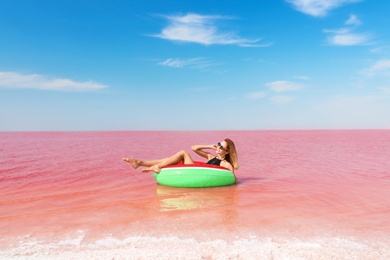 Photo of Beautiful woman on inflatable ring in pink lake