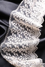 Beautiful white lace on black fabric, top view