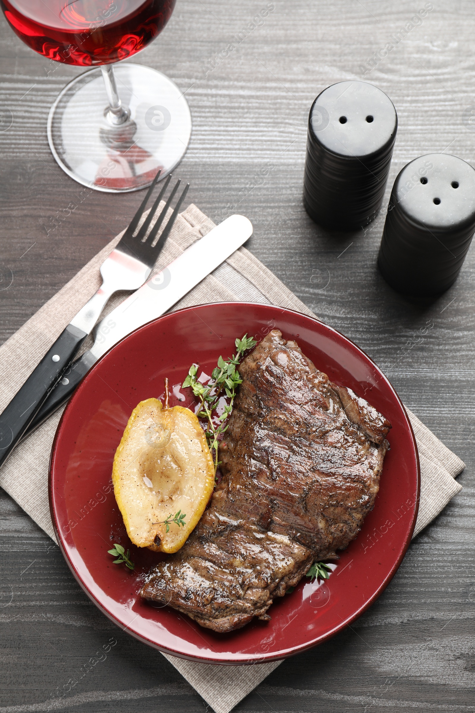 Photo of Delicious roasted beef meat, caramelized pear and thyme served on grey wooden table, flat lay