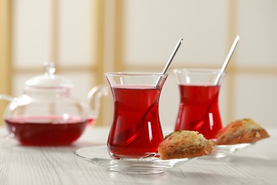 Glasses of traditional Turkish tea and sweet baklava on white wooden table indoors