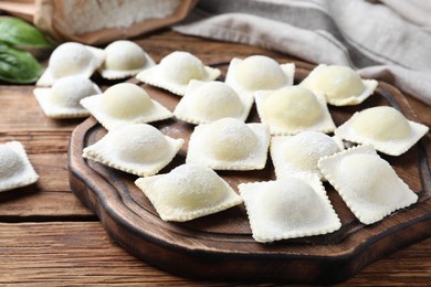 Photo of Homemade uncooked ravioli on wooden table, closeup