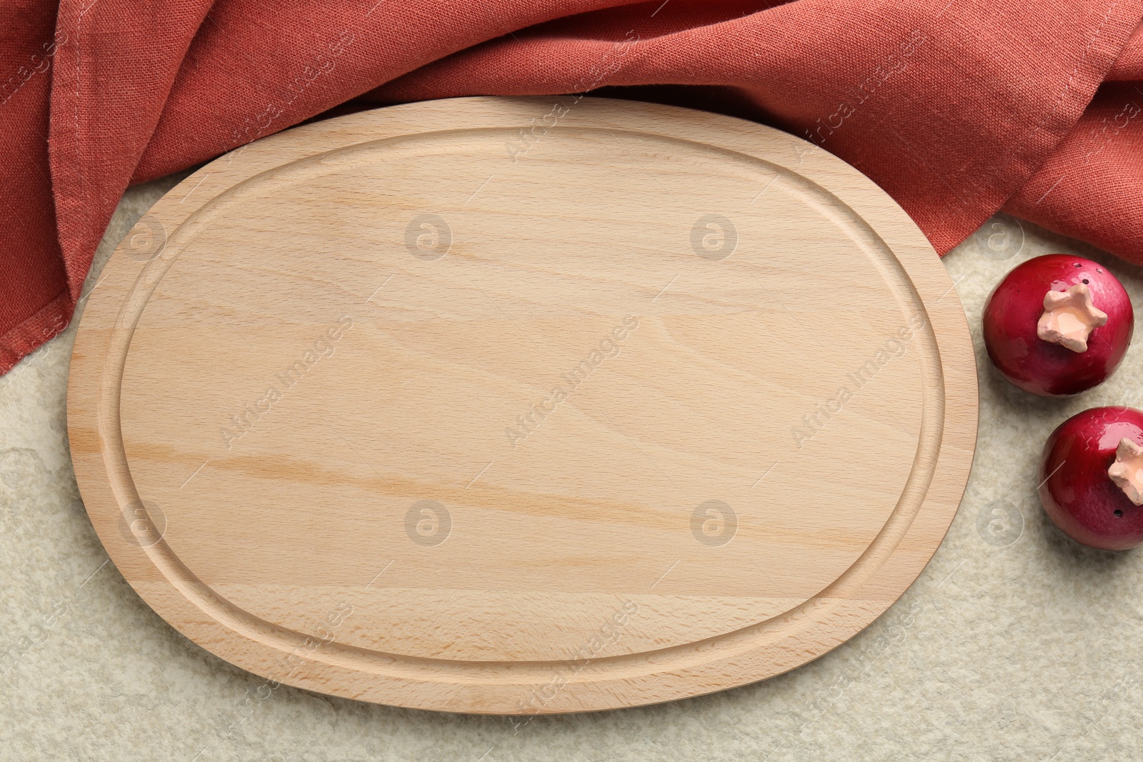 Photo of Wooden cutting board, cloth and spice shakers on beige table, flat lay. Space for text