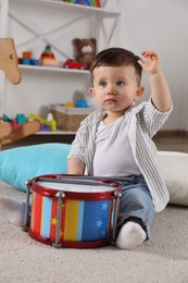 Cute little boy with toy drum at home