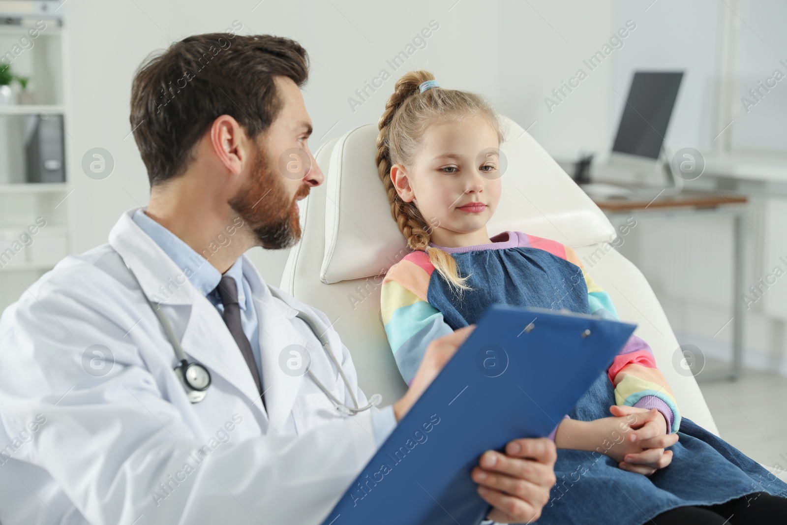 Photo of Pediatrician with clipboard consulting patient in clinic