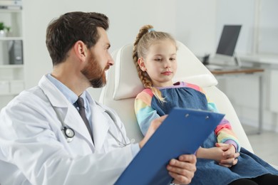 Pediatrician with clipboard consulting patient in clinic