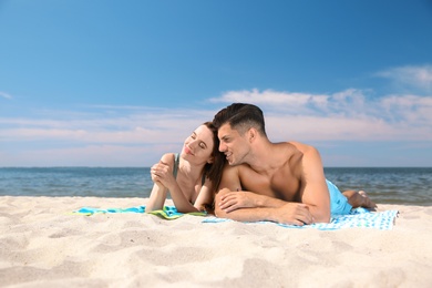 Photo of Beautiful woman and her boyfriend sunbathing on beach. Happy couple