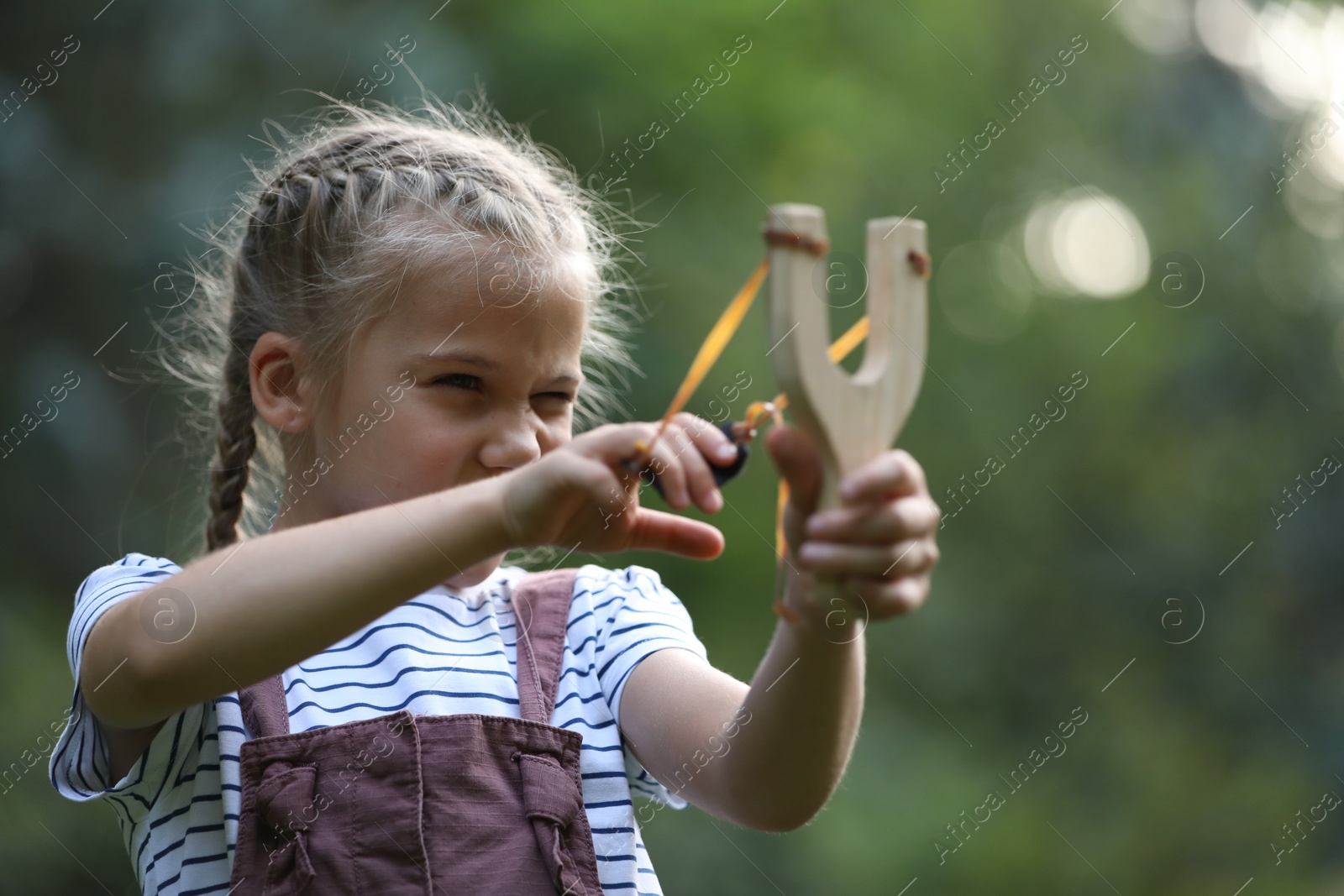 Photo of Little girl playing with slingshot in park