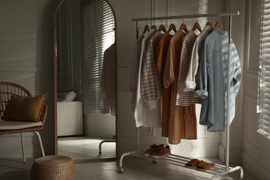 Photo of Modern dressing room interior with stylish clothes, shoes and large mirror