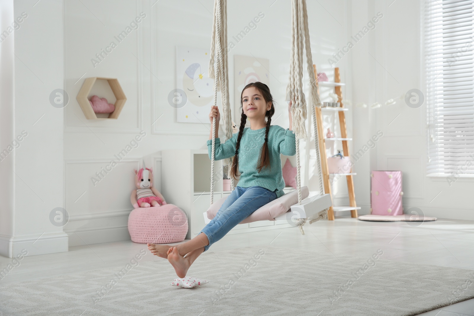 Photo of Cute little girl playing on swing at home