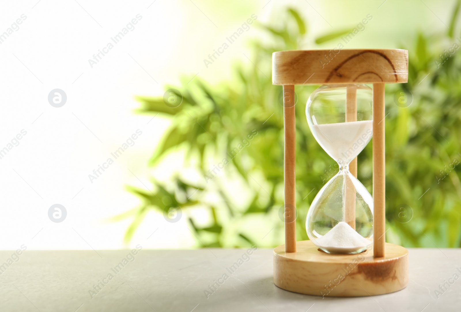 Photo of Hourglass with flowing sand on table against blurred background. Time management