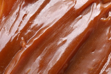 Photo of Tasty sweet caramel sauce as background, above view