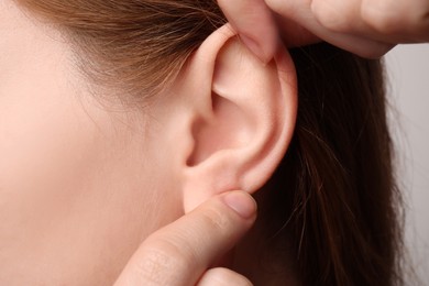 Photo of Woman touching her ear on light grey background, closeup