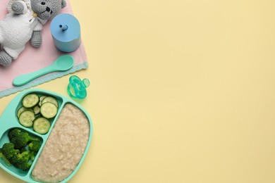 Photo of Healthy baby food in plate and accessories on yellow background, flat lay. Space for text