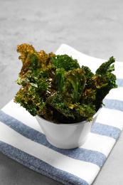 Tasty baked kale chips on grey table