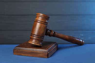 Photo of Wooden gavel and sound block on blue table, closeup