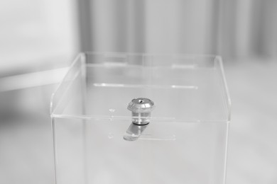 Photo of Transparent ballot box on blurred background, closeup